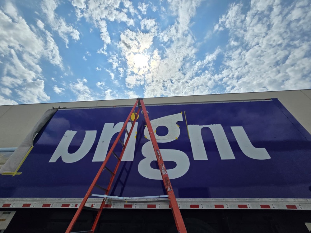 New white vinyl letters being laid on the box side, transfer paper still on the g