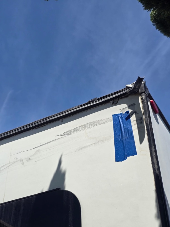 Rear corner of a white box with scrapes and a damaged corner cap