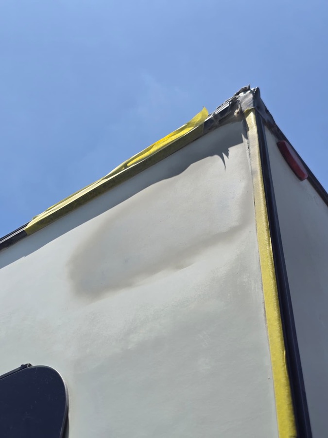 Same corner with body filler applied and masked with yellow tape