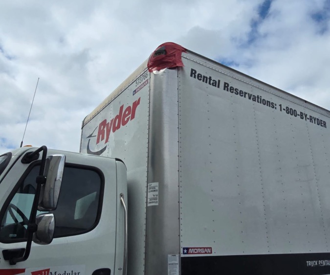 Box truck corner with damage covered in tape before the corner cap and radius replacement