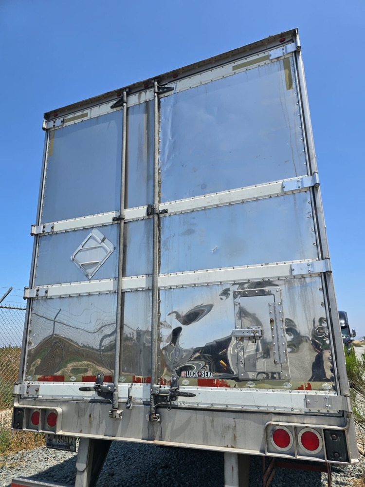 Trailer rear doors closed, the right door creased and buckled