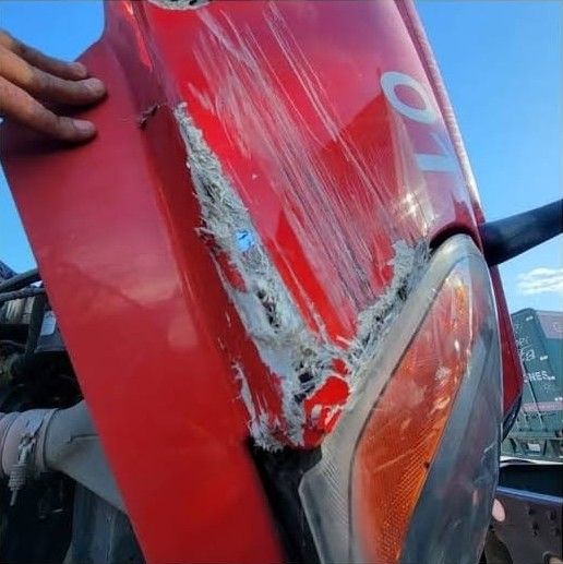 Close-up of the torn, scraped red fender above the headlight