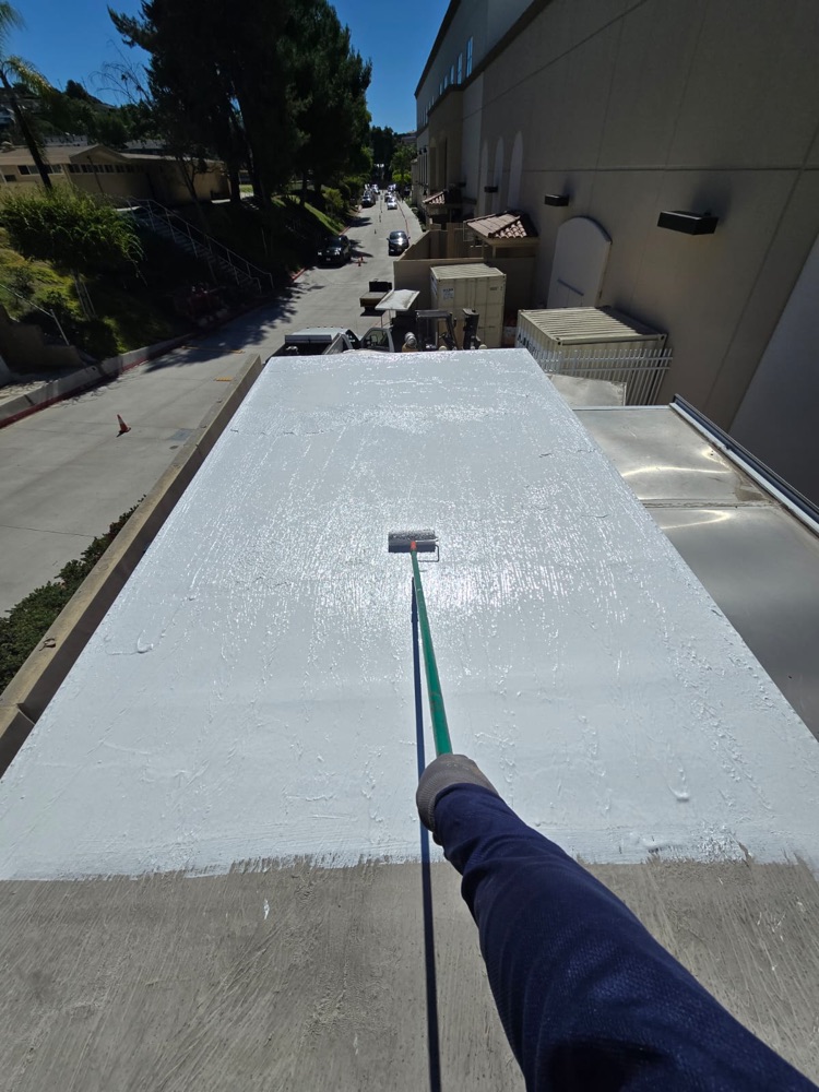 Rolling white coating onto a box truck roof