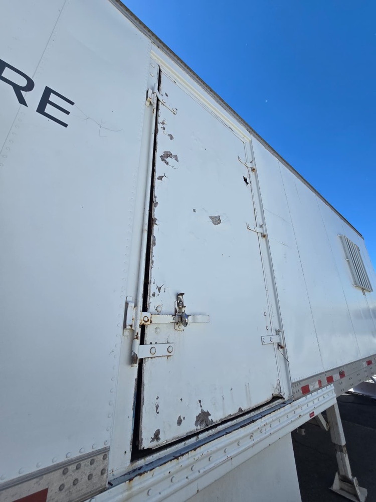 Trailer side access door rusted and peeling with a gap along the edge
