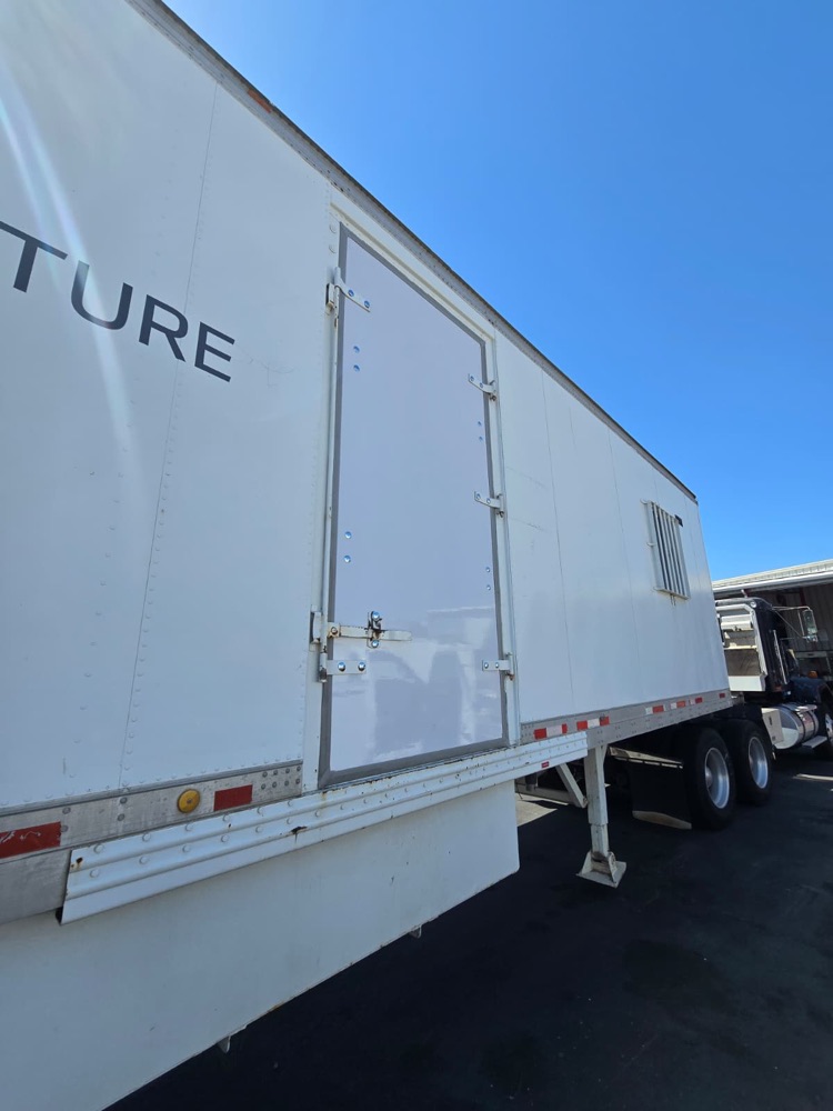 Same trailer side access door replaced with a clean new panel, angled view