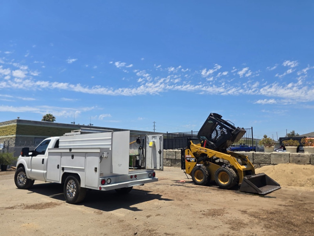 Service truck set up beside the skid steer with the cab tilted up for access