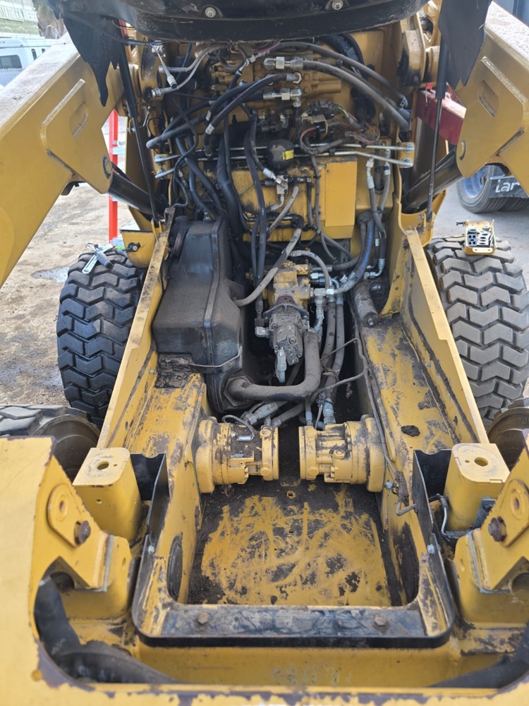 Skid steer hydraulic compartment opened up with the pumps, motors and hoses exposed