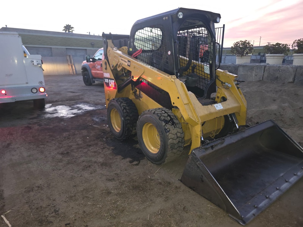 Repaired skid steer back on the ground with the cab down and the service truck beside it