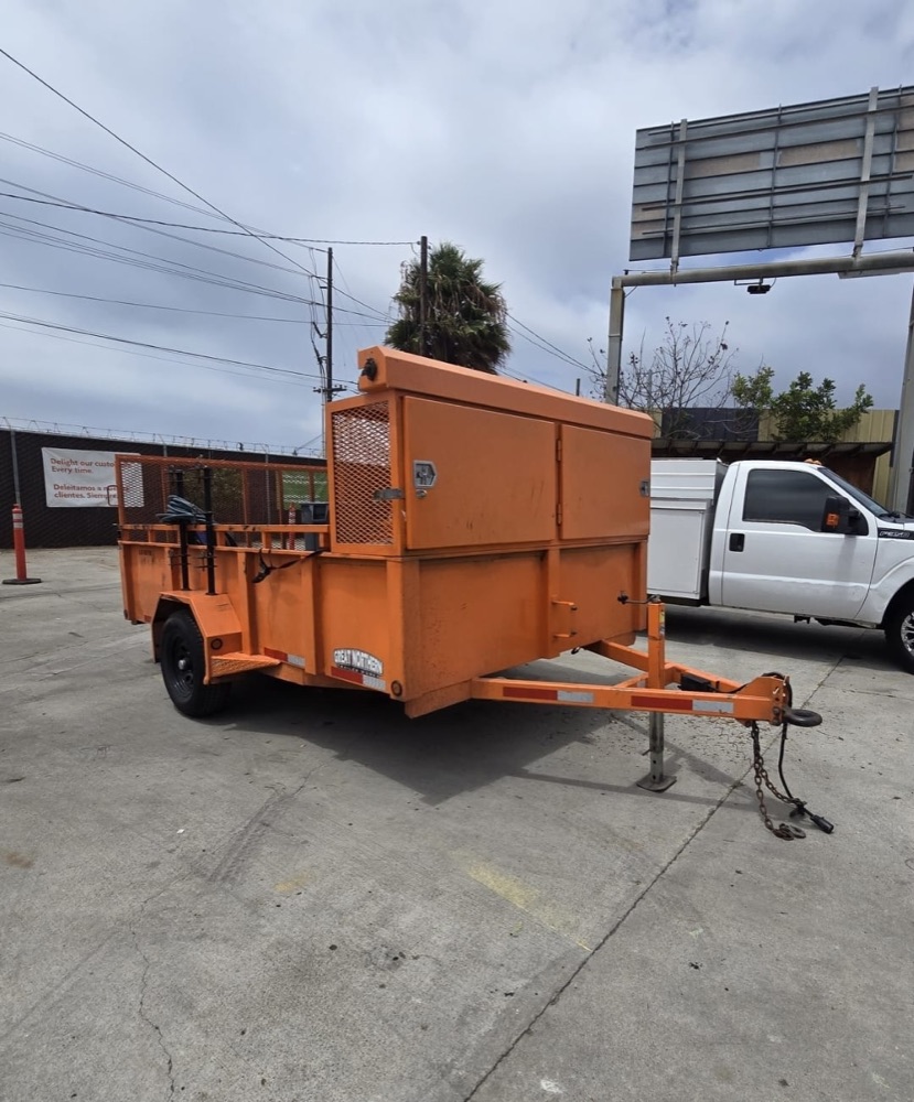 Orange utility trailer with a built-in storage box at the front, parked and ready to tow