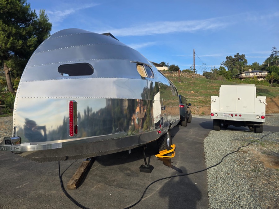 Side and rear of the polished aluminum travel trailer on a driveway